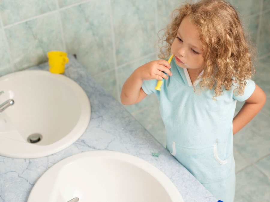 A young girl brushing her teeth at the bathroom sink