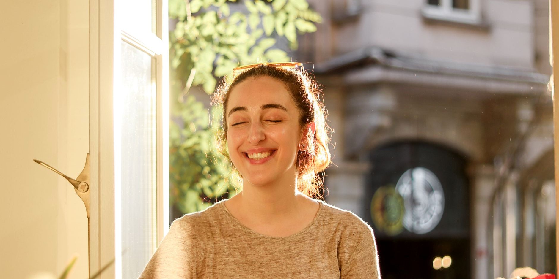 A woman smiling with her eyes closed in warm light