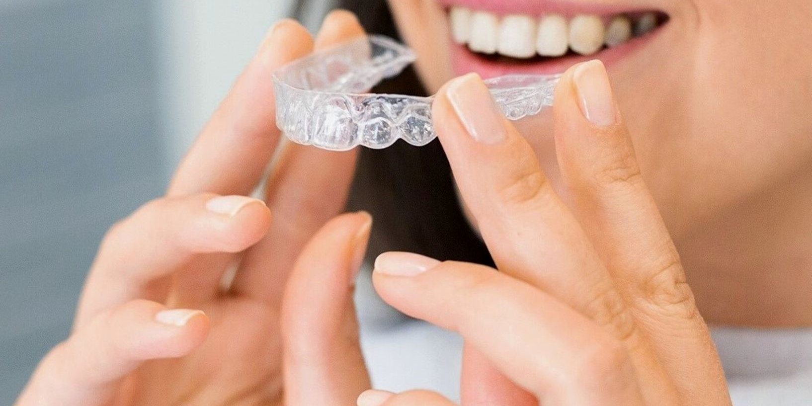 A woman holding a clear aligner