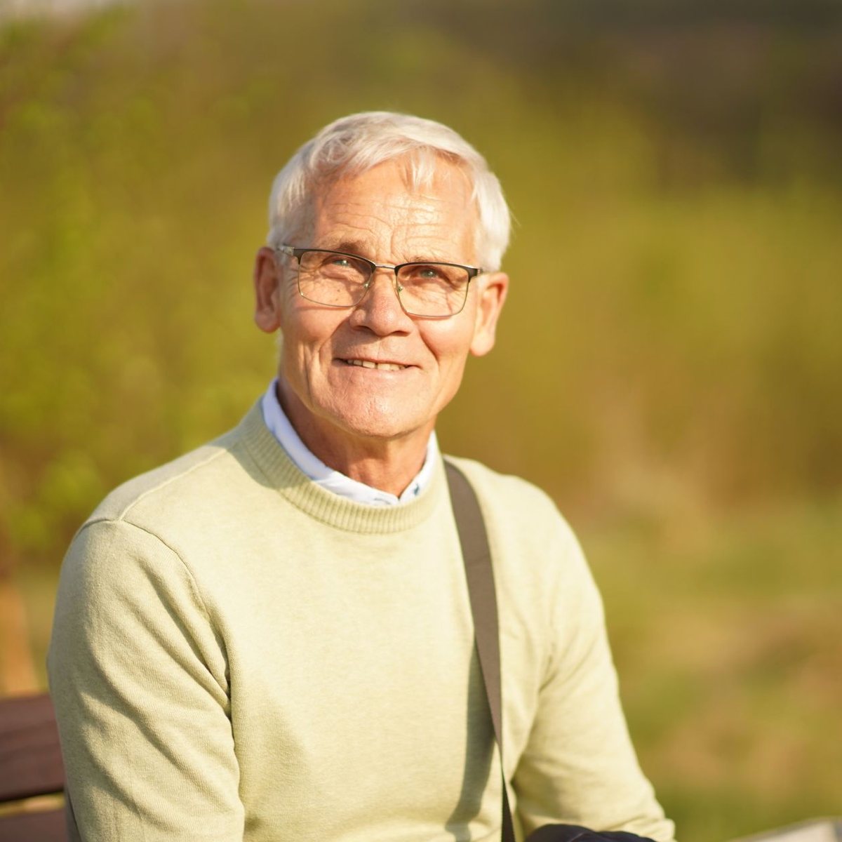 An older man smiling outdoors
