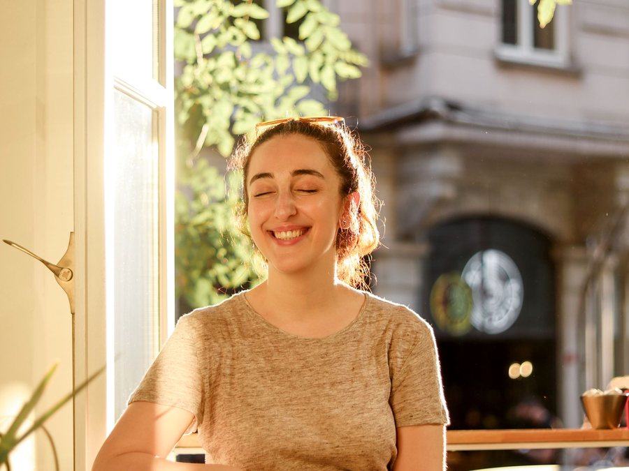 A woman smiling with her eyes closed in warm light