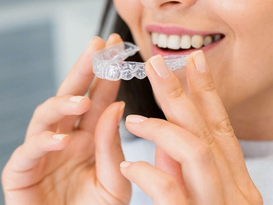 A woman holding a clear aligner