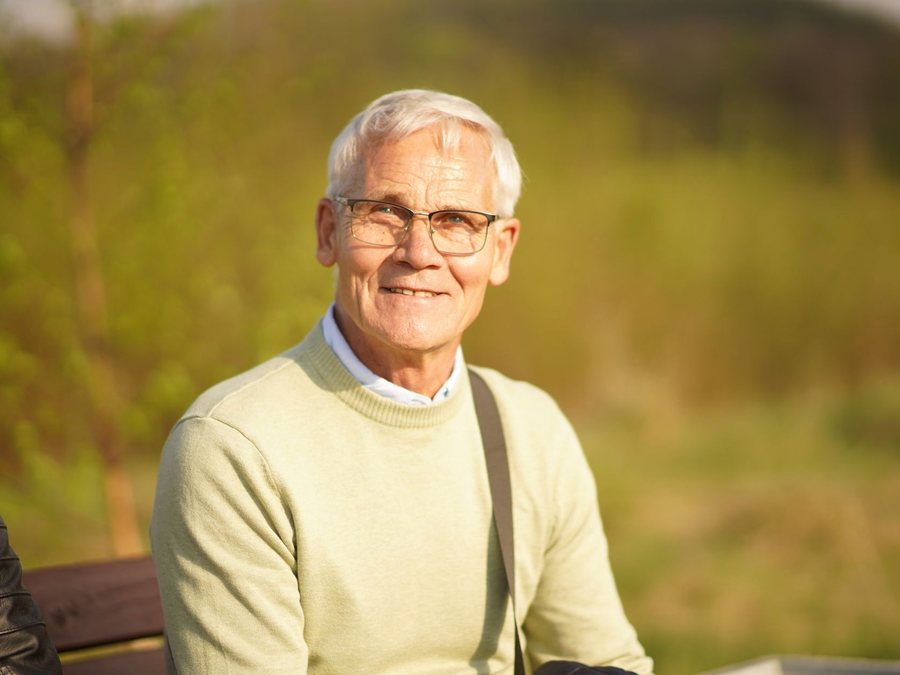 An older man smiling outdoors