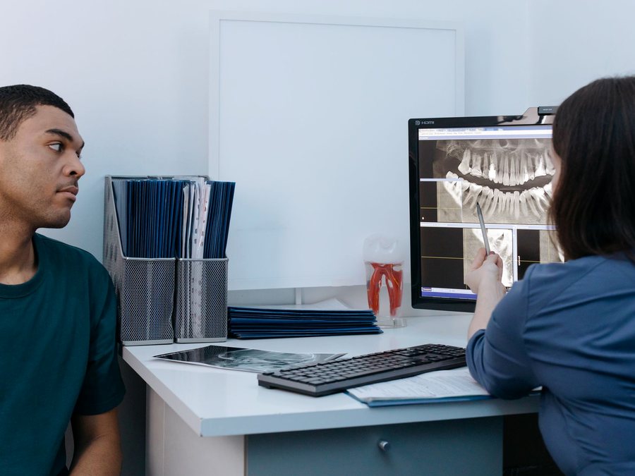 A dentist showing a patient their x-ray on screen